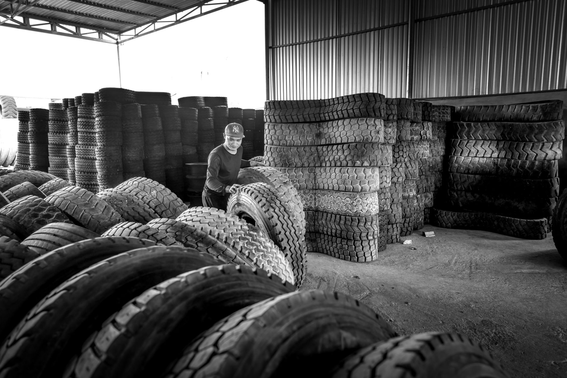 Rolls of black industrial rubber sheet stacked in a warehouse