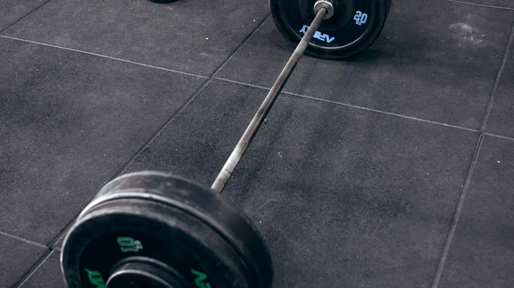 Black rubber tile gym flooring with a loaded barbell