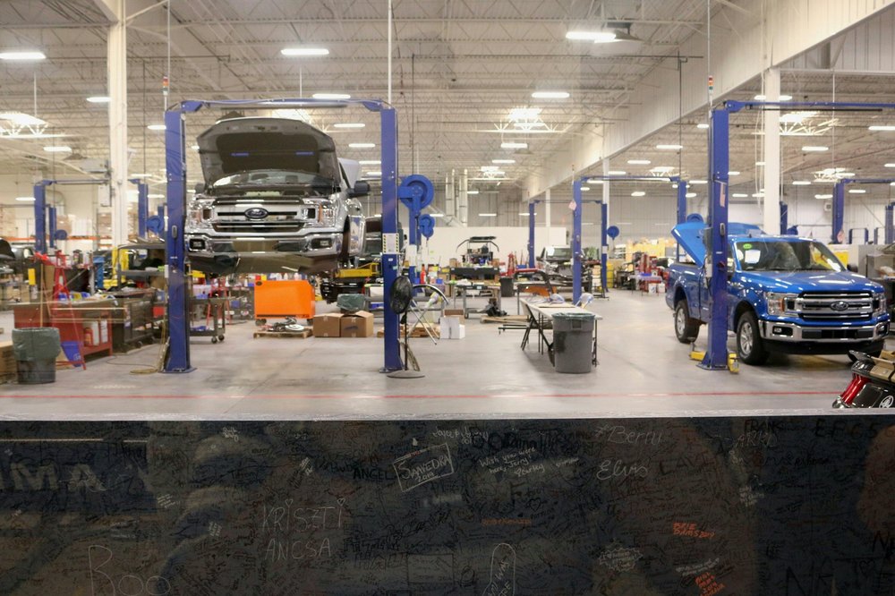 Indoor automotive workshop with two trucks on lifts