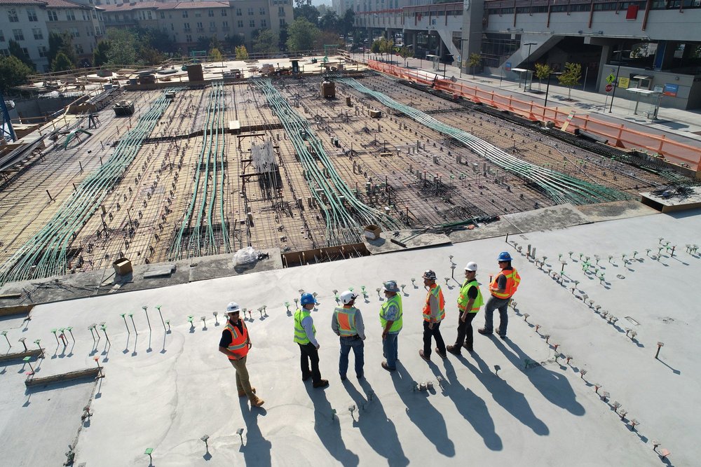 Construction workers in safety vests on a concrete rooftop